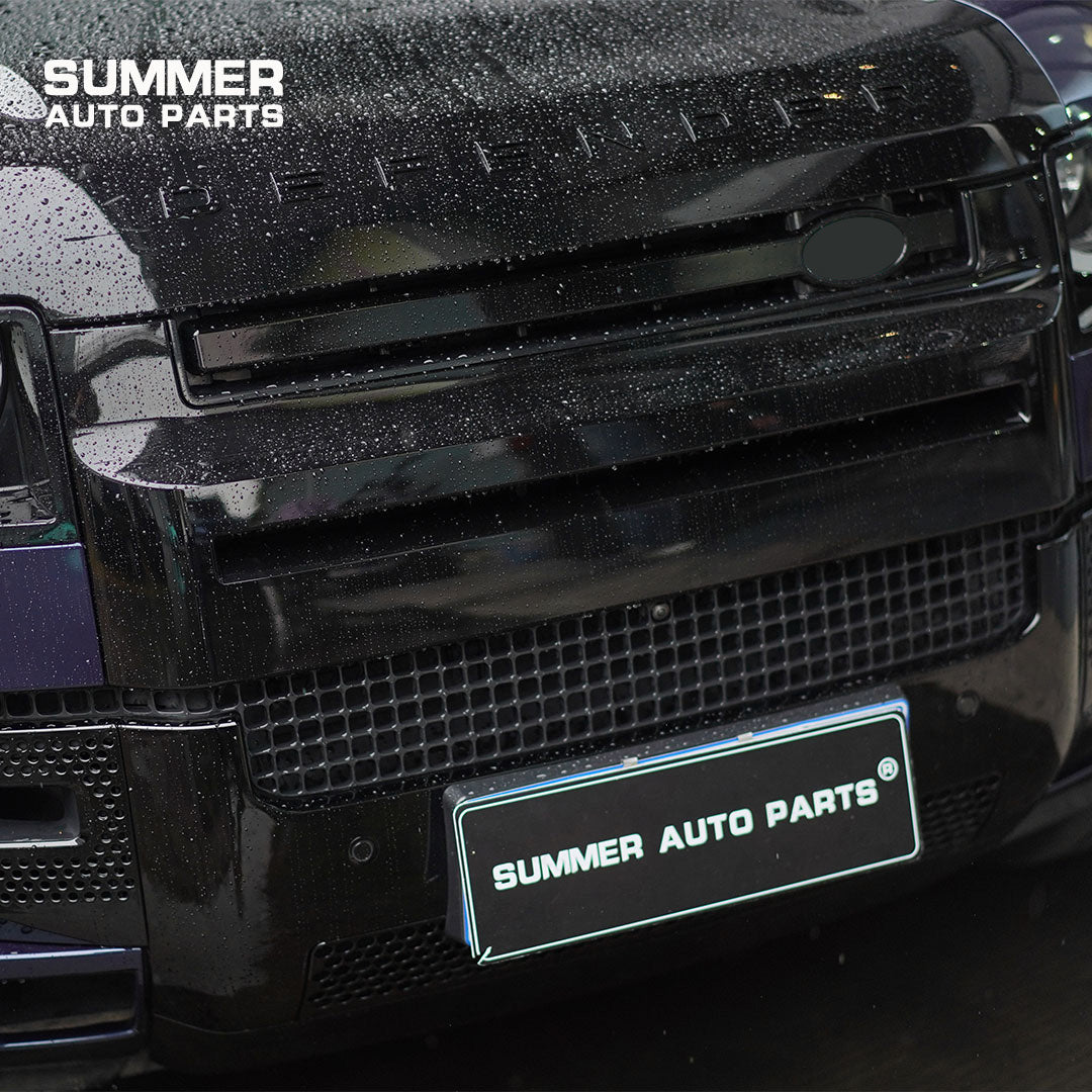 Close-up of installed gloss black front grille and bumper trim on Land Rover Defender L663